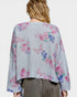 Woman wearing a gray cardigan with colorful butterfly patterns on a plain background