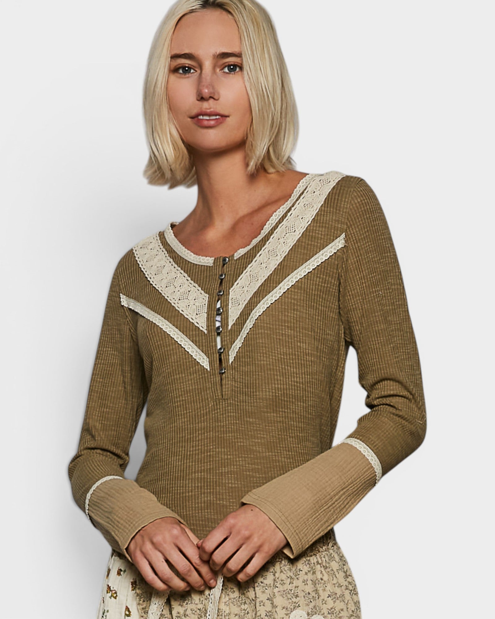 Woman wearing a brown long-sleeve top with lace details on a white background