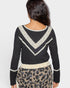 Person wearing a black sweater with white lace details and a leopard print skirt on a light gray background