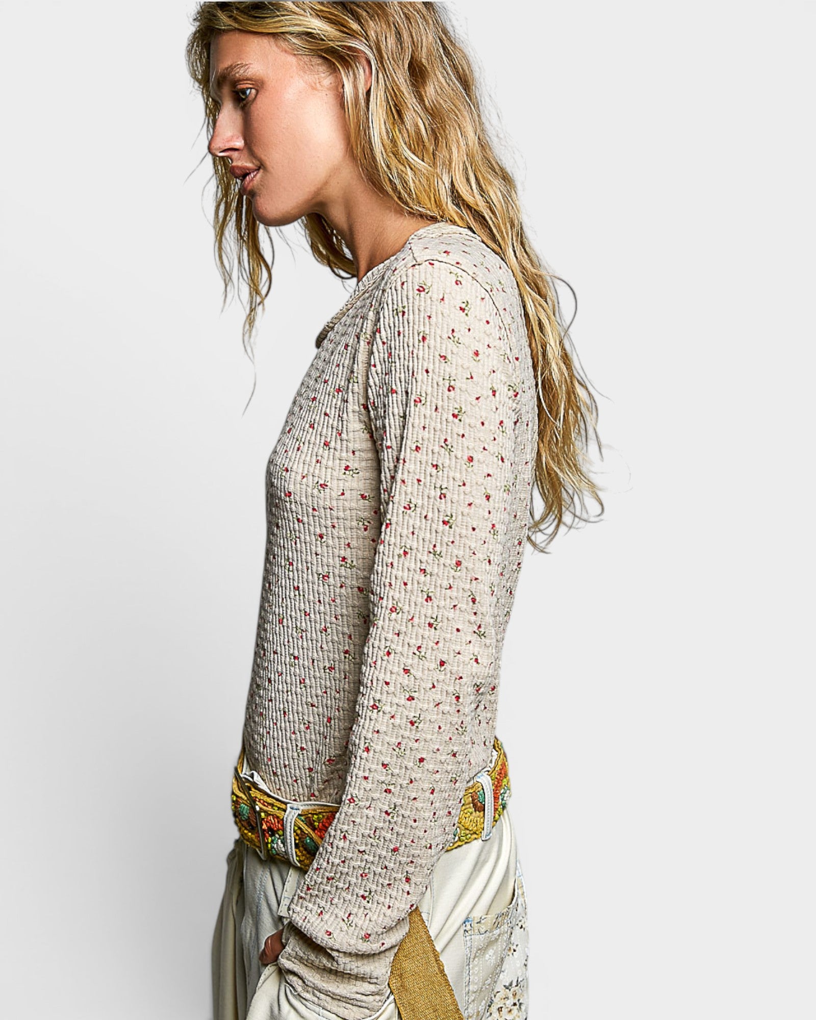 Woman wearing a patterned top with a colorful belt on a white background