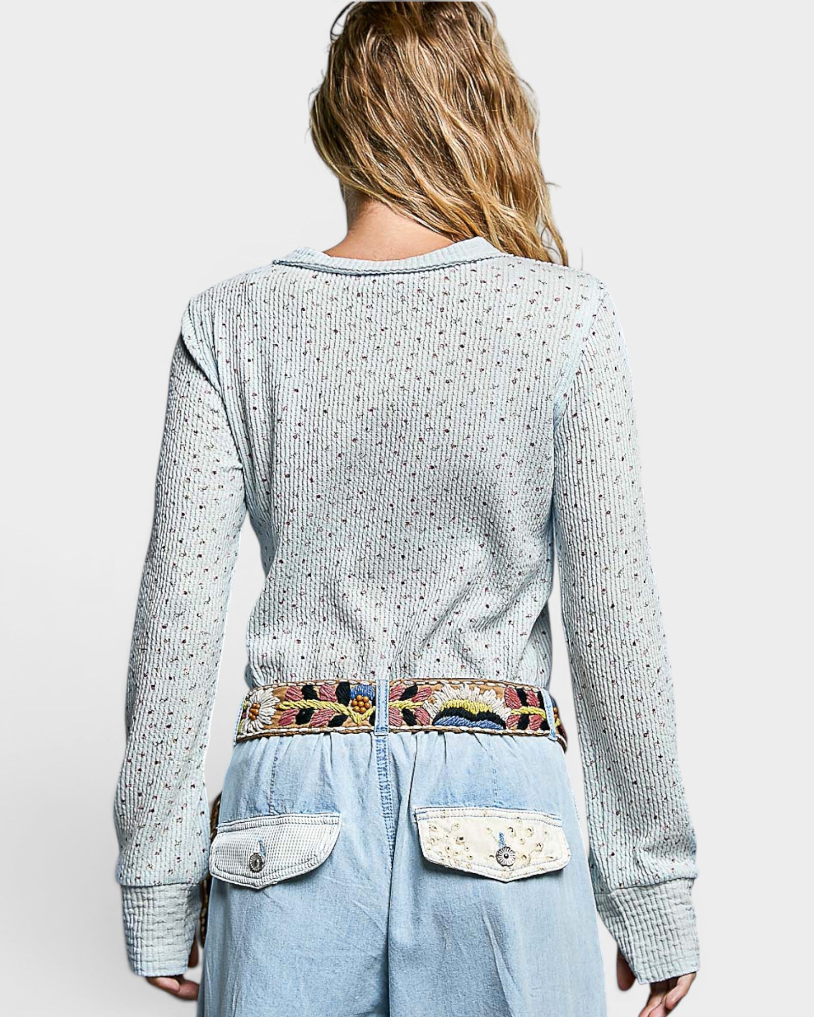 Person wearing a light gray textured sweater with colorful patterned front panel on a white background