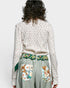 Person wearing a floral-patterned top and green skirt with floral pockets on a white background