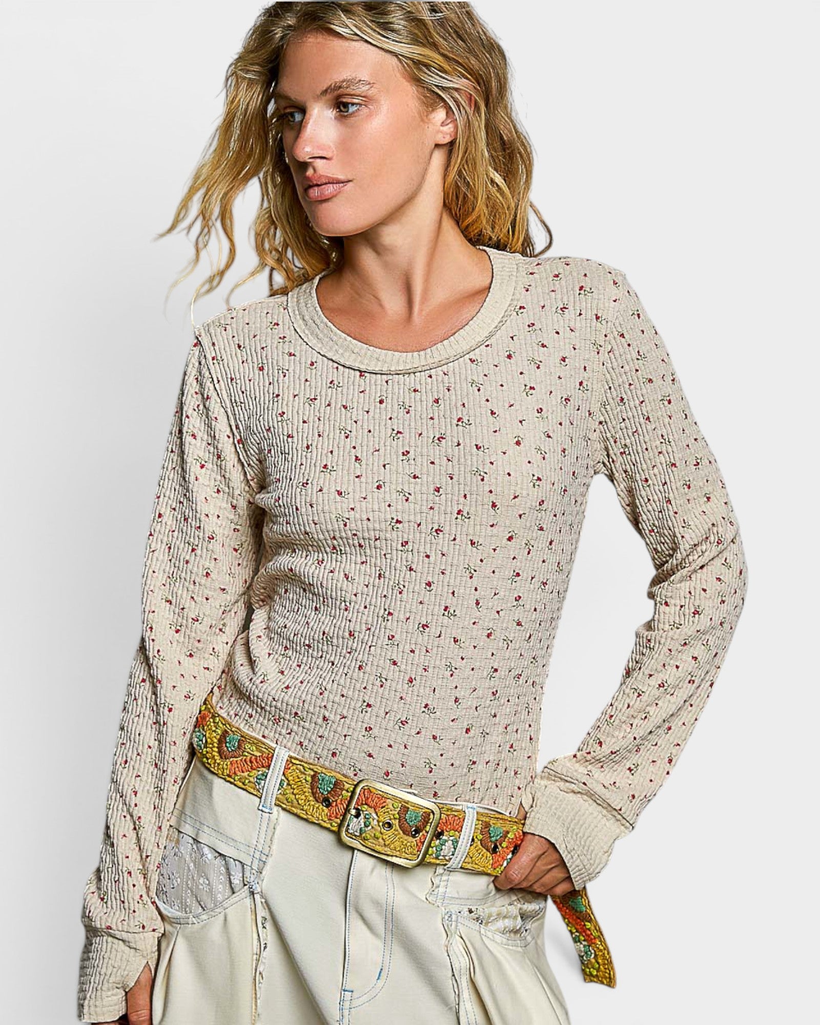 Woman wearing a patterned sweater and colorful belt against a plain background