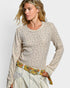Woman wearing a patterned sweater and colorful belt against a plain background
