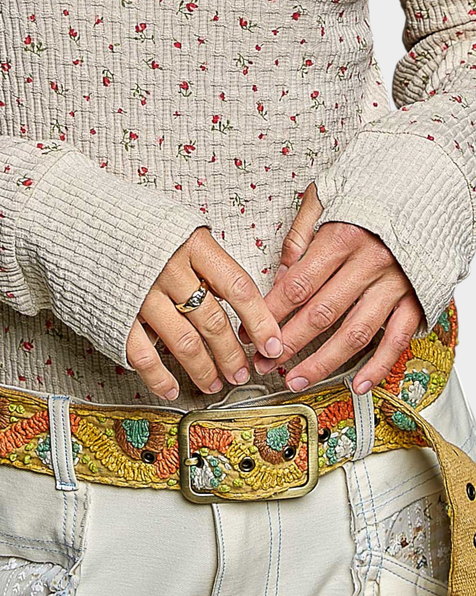 Close-up of hands adjusting a floral-patterned belt with an owl design.