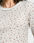 Close-up of a person wearing a white textured shirt with small red floral patterns.