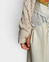Close-up of a person wearing a patterned shirt and light-colored pants against a plain background