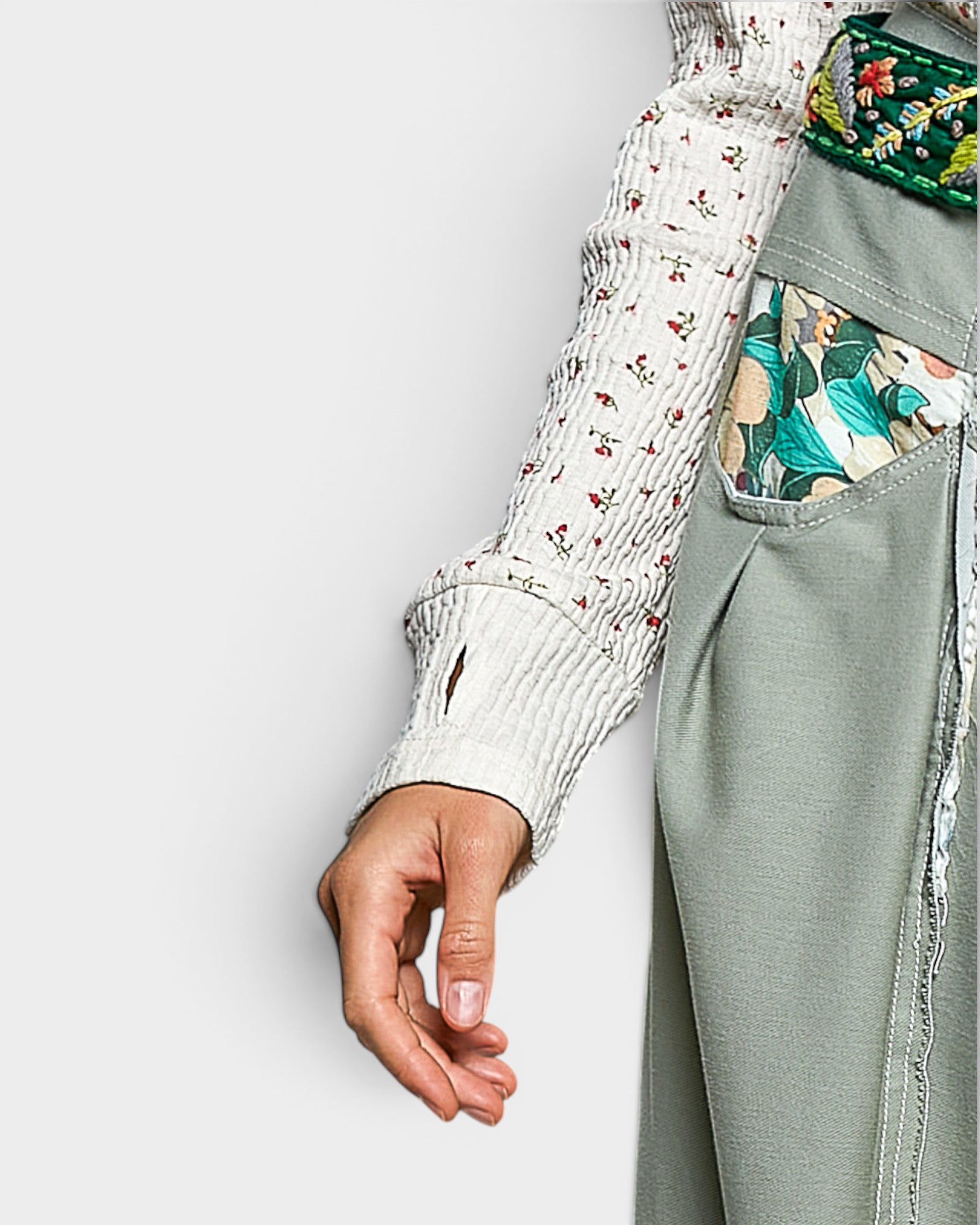 Person wearing a floral shirt and green pants with a white background