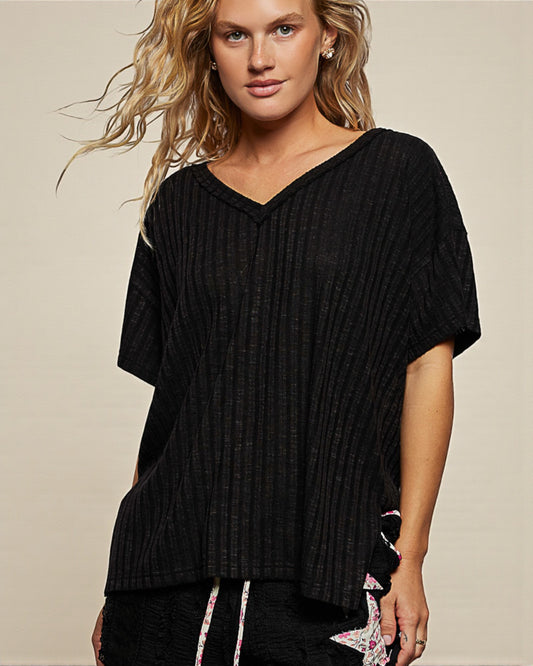 Woman wearing a black ribbed sweater against a beige background