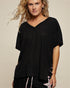Woman wearing a black ribbed sweater against a beige background