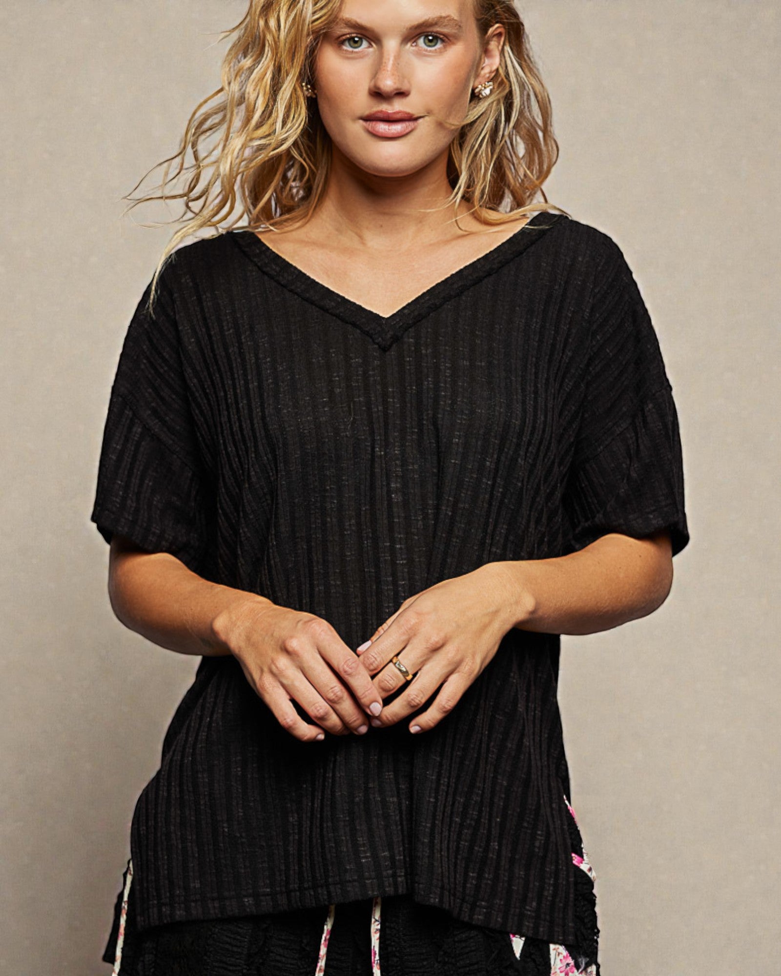 Woman wearing a black ribbed sweater against a beige background