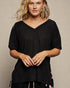 Woman wearing a black ribbed sweater against a beige background
