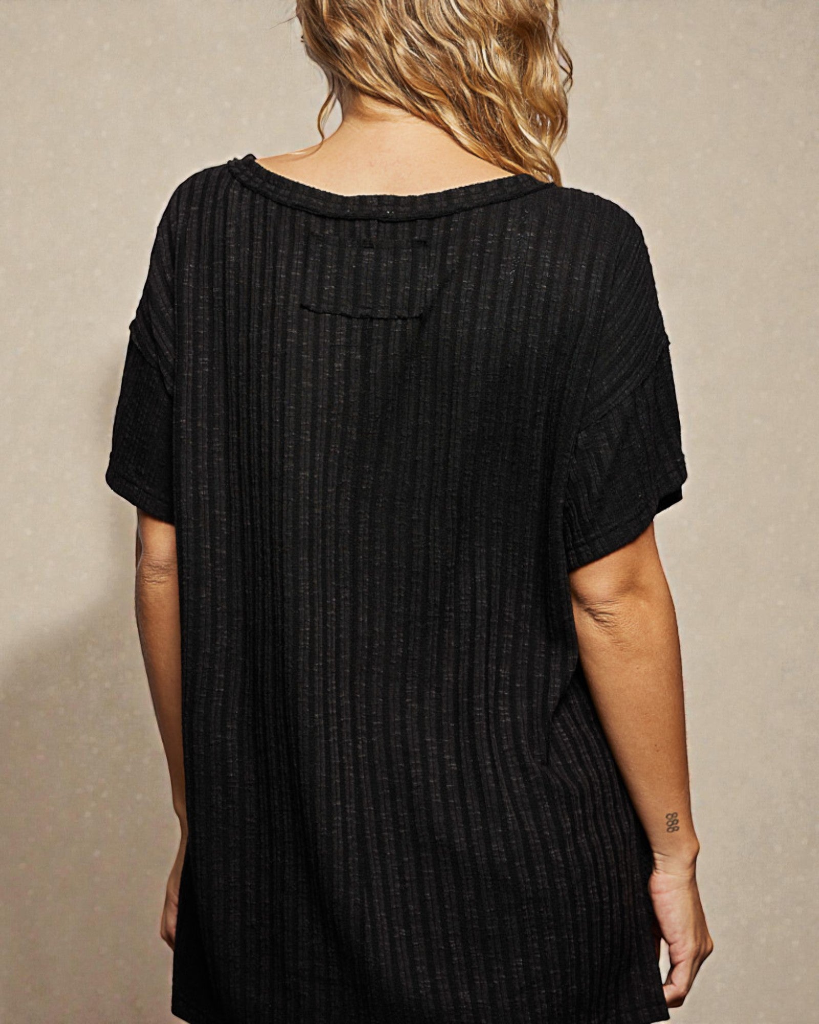 Black textured dress worn by a person on a beige background