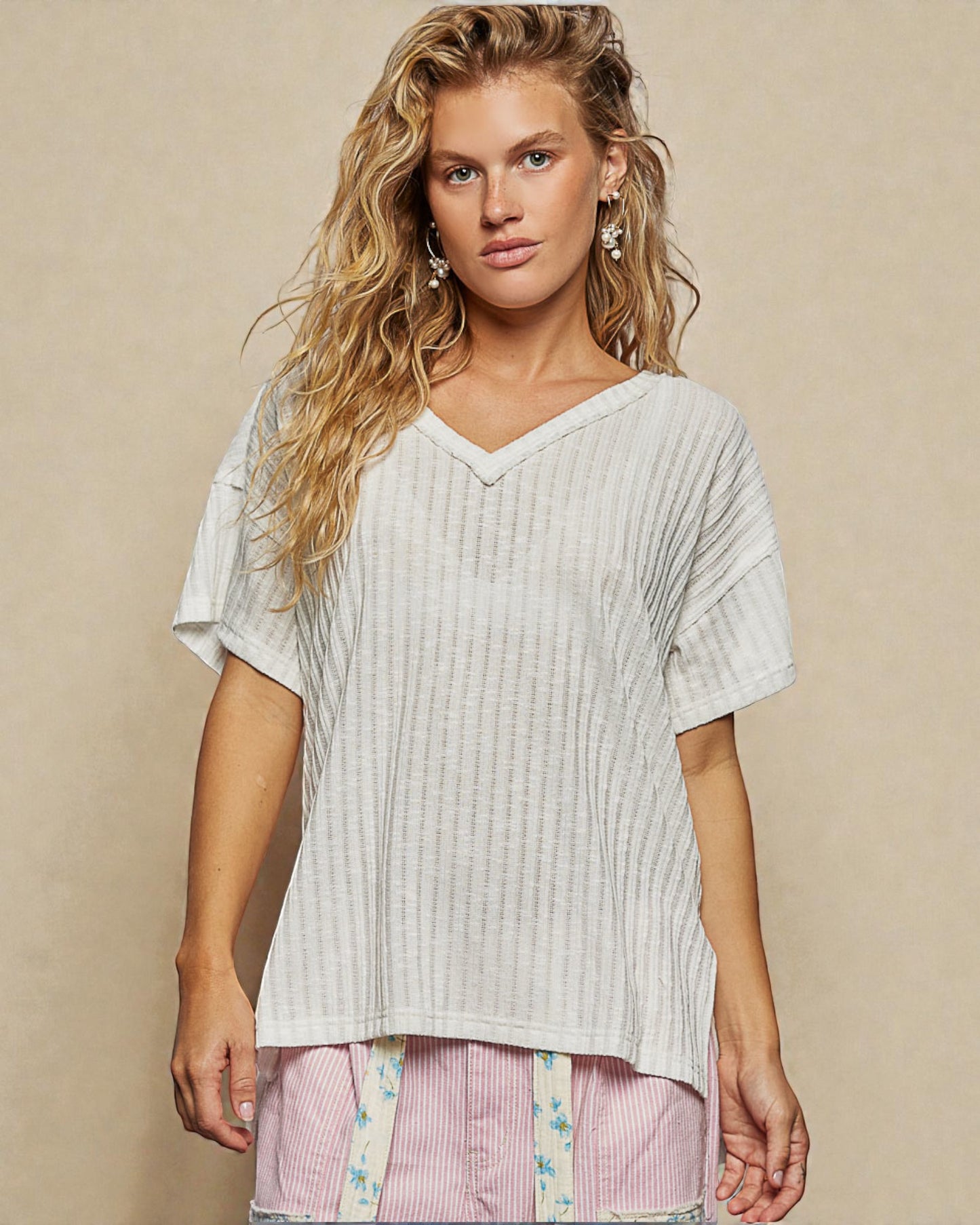 Woman wearing a light-colored ribbed top against a beige background