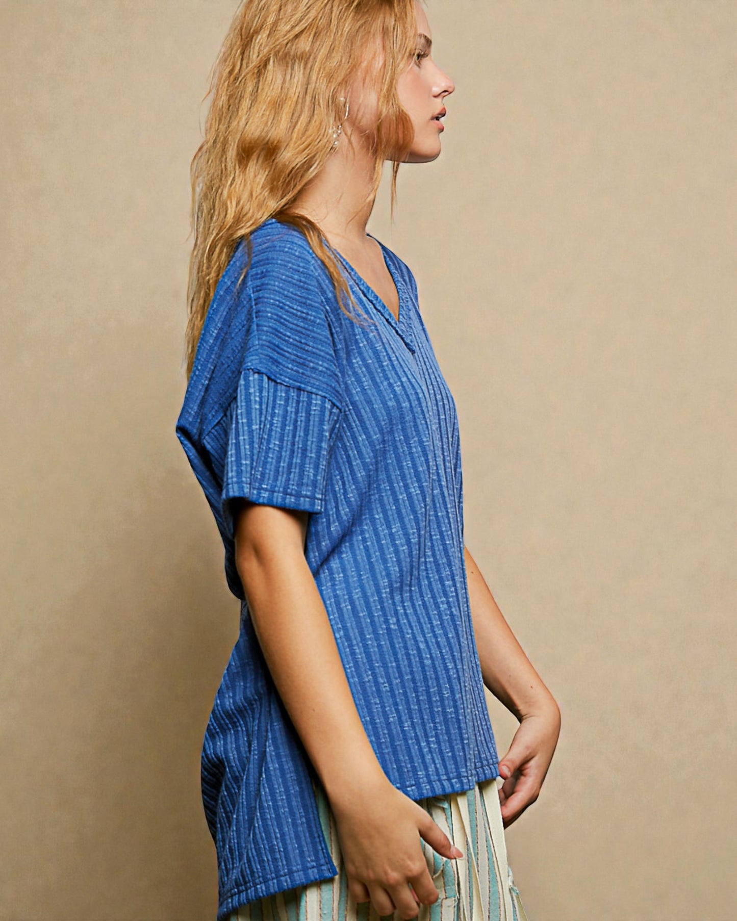 Woman wearing a blue textured top against a beige background