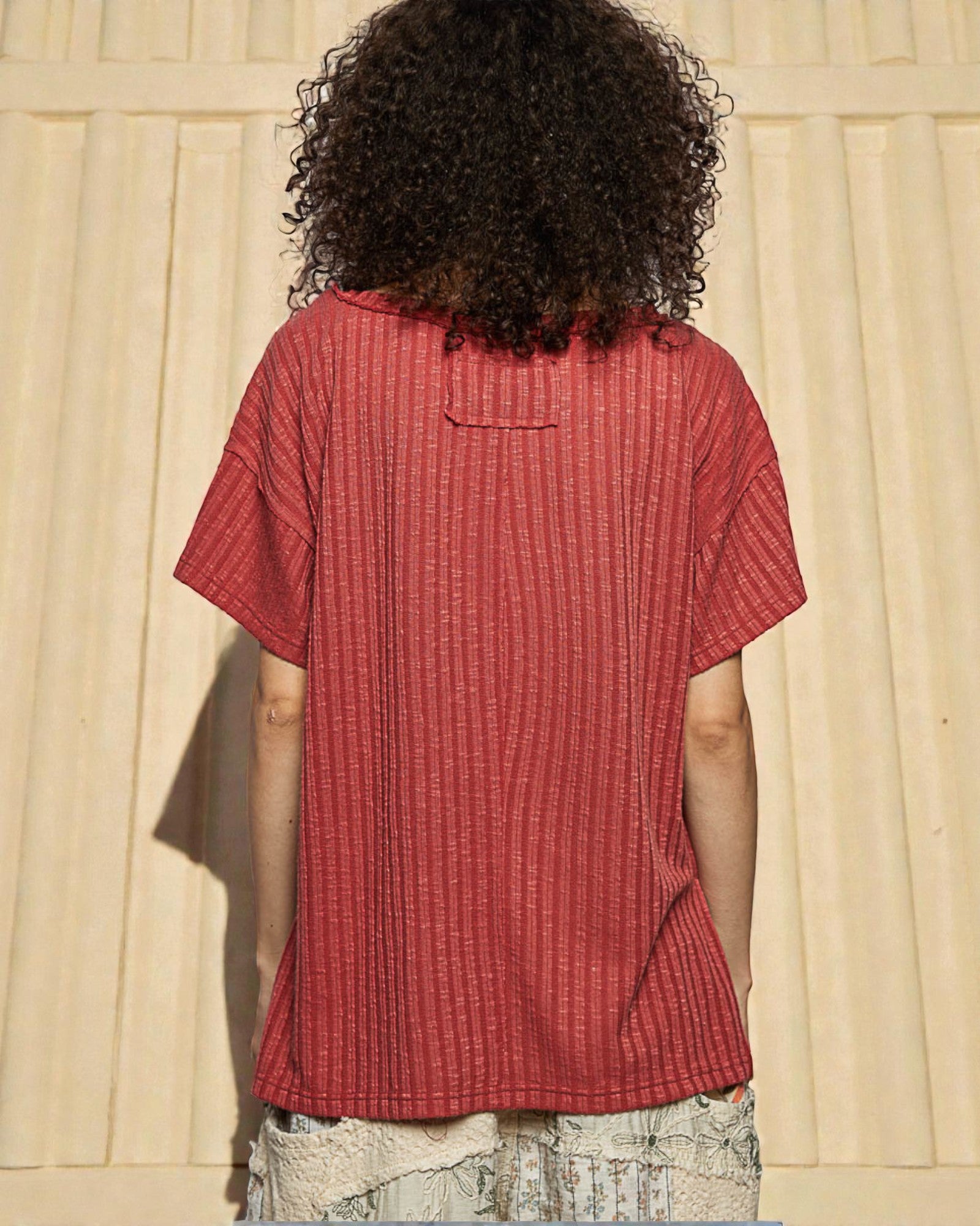Person wearing a red textured shirt with a neutral background
