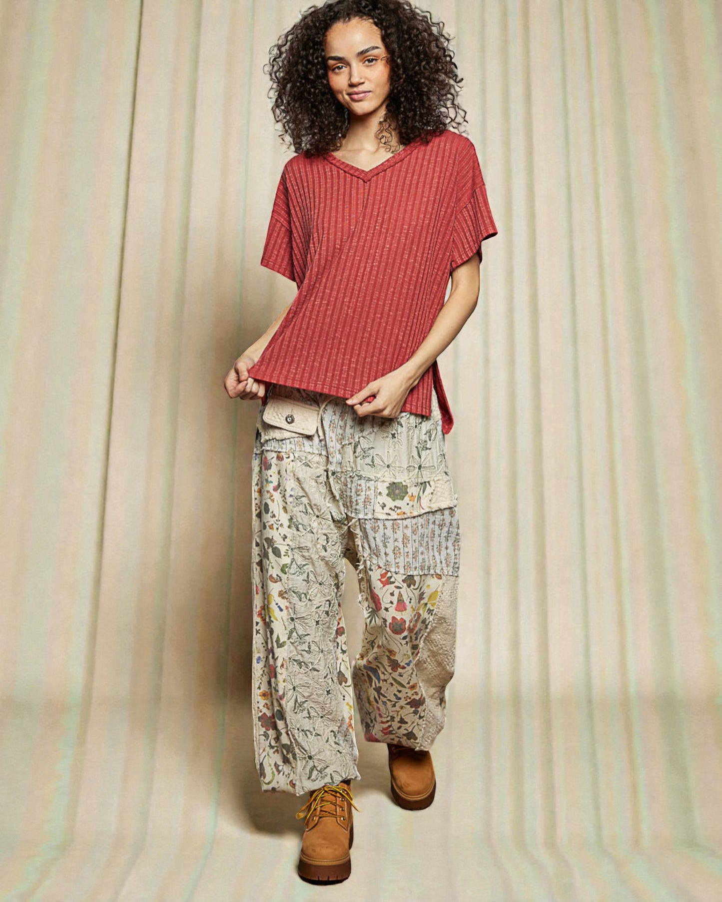 Woman wearing a red top and patterned pants against a neutral background