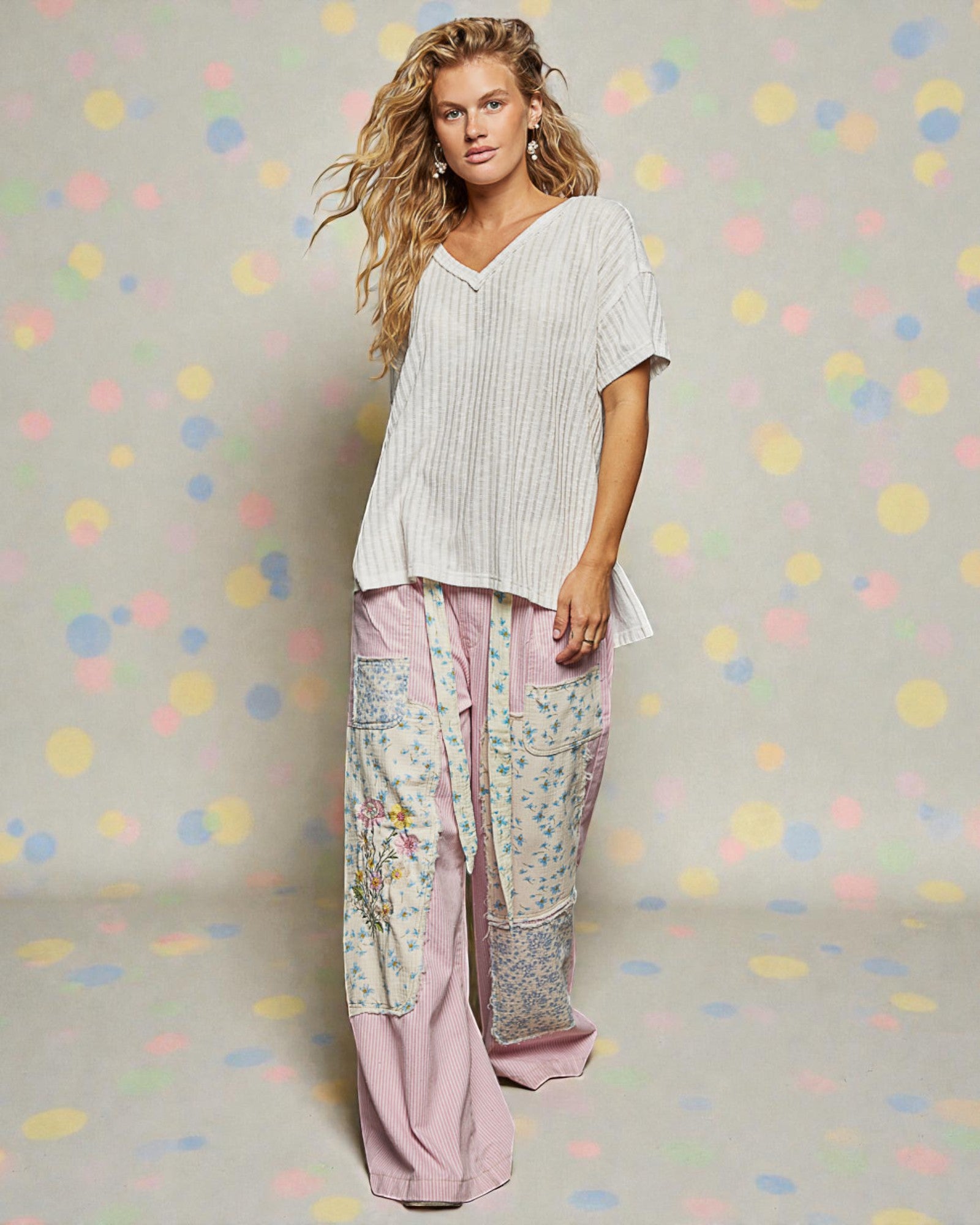 Woman wearing a white top and patterned pants against a polka dot background