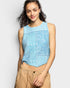 Woman wearing a light blue sleeveless top with lace details on a plain background
