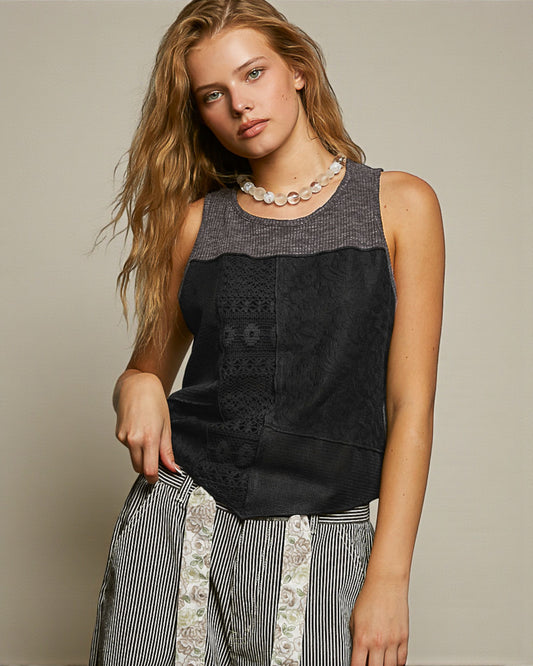 Woman wearing a black sleeveless top with patterned trim against a neutral background