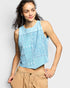 Woman wearing a light blue sleeveless top with lace details on a plain background