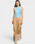 Woman wearing a light blue sleeveless top and beige patchwork pants on a white background