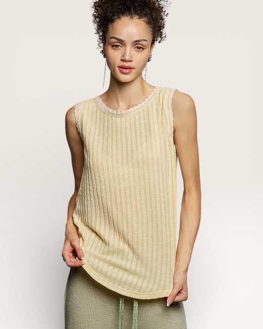 Woman wearing a beige sleeveless top against a plain background