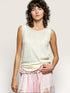 Woman wearing a sleeveless ribbed top and pink skirt with lace details on a plain background
