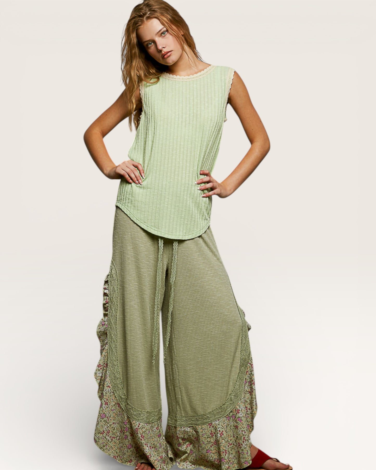 Woman wearing a green sleeveless top and wide-leg pants on a white background