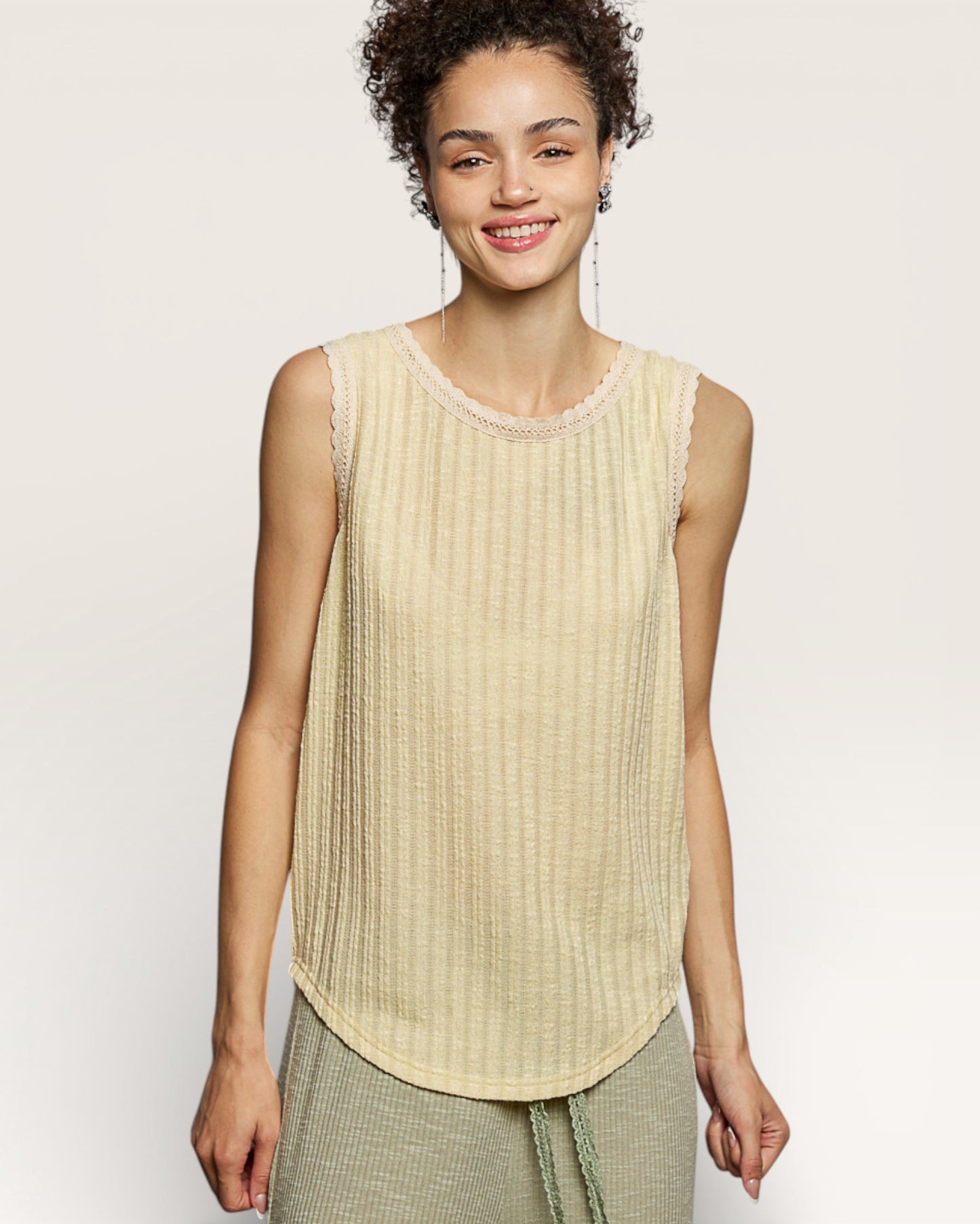 Woman wearing a beige sleeveless top with a plain background