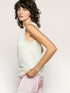 Woman wearing a light-colored sleeveless top with a plain background