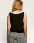 Woman wearing a black sleeveless top with white trim on a plain background