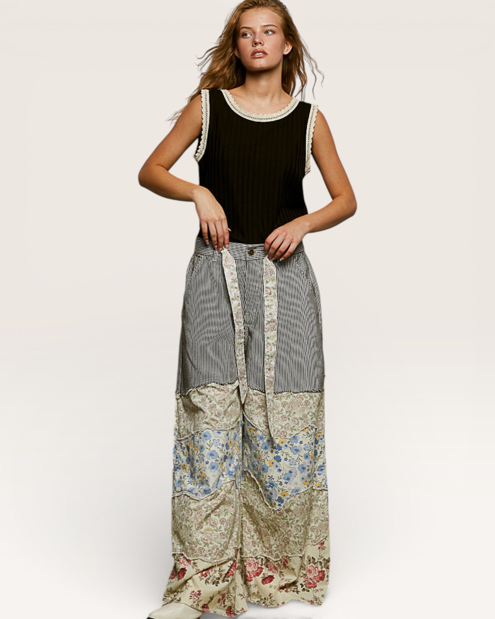 Woman wearing a black sleeveless top and patchwork pants on a white background