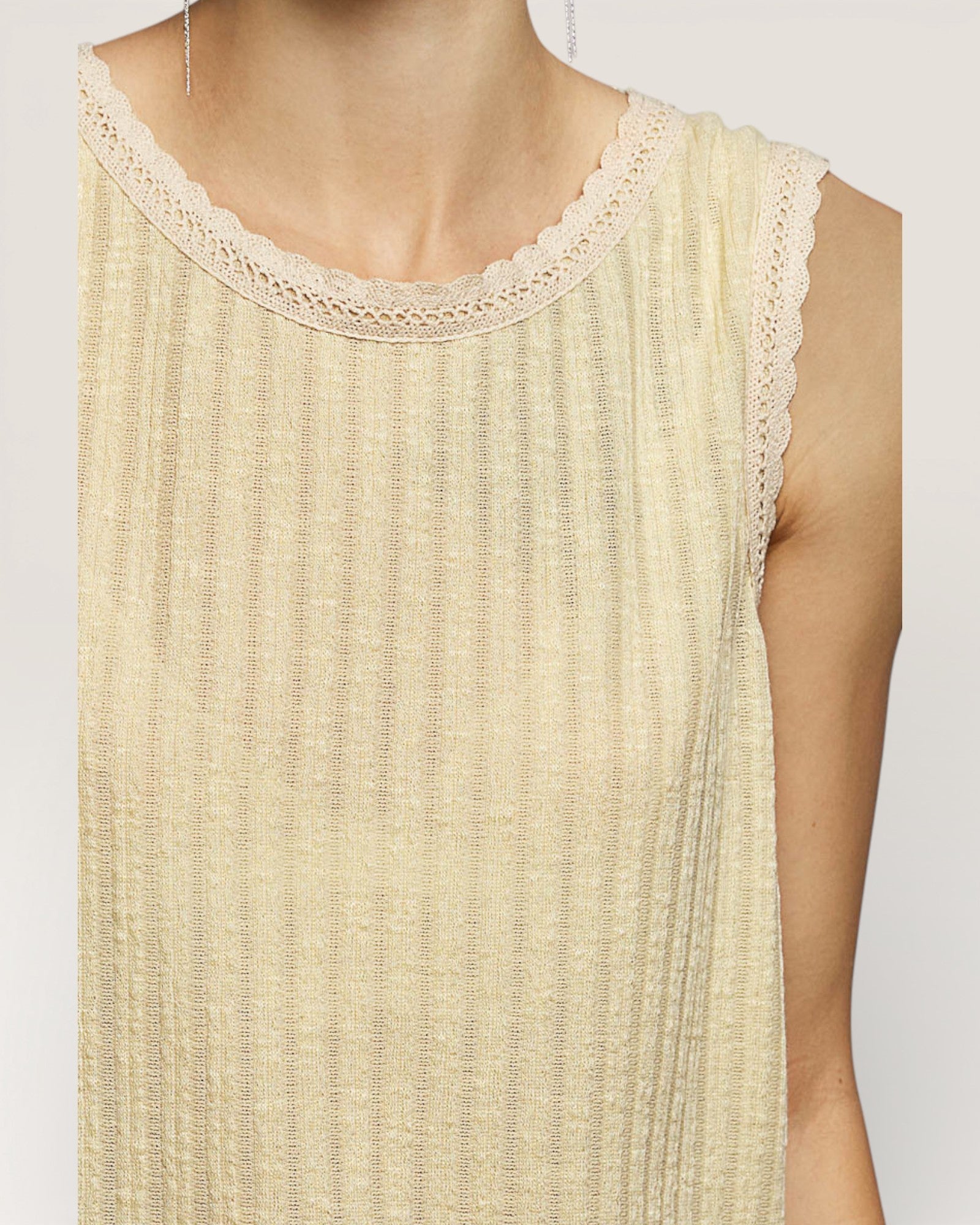 Beige sleeveless top with lace neckline on a white background
