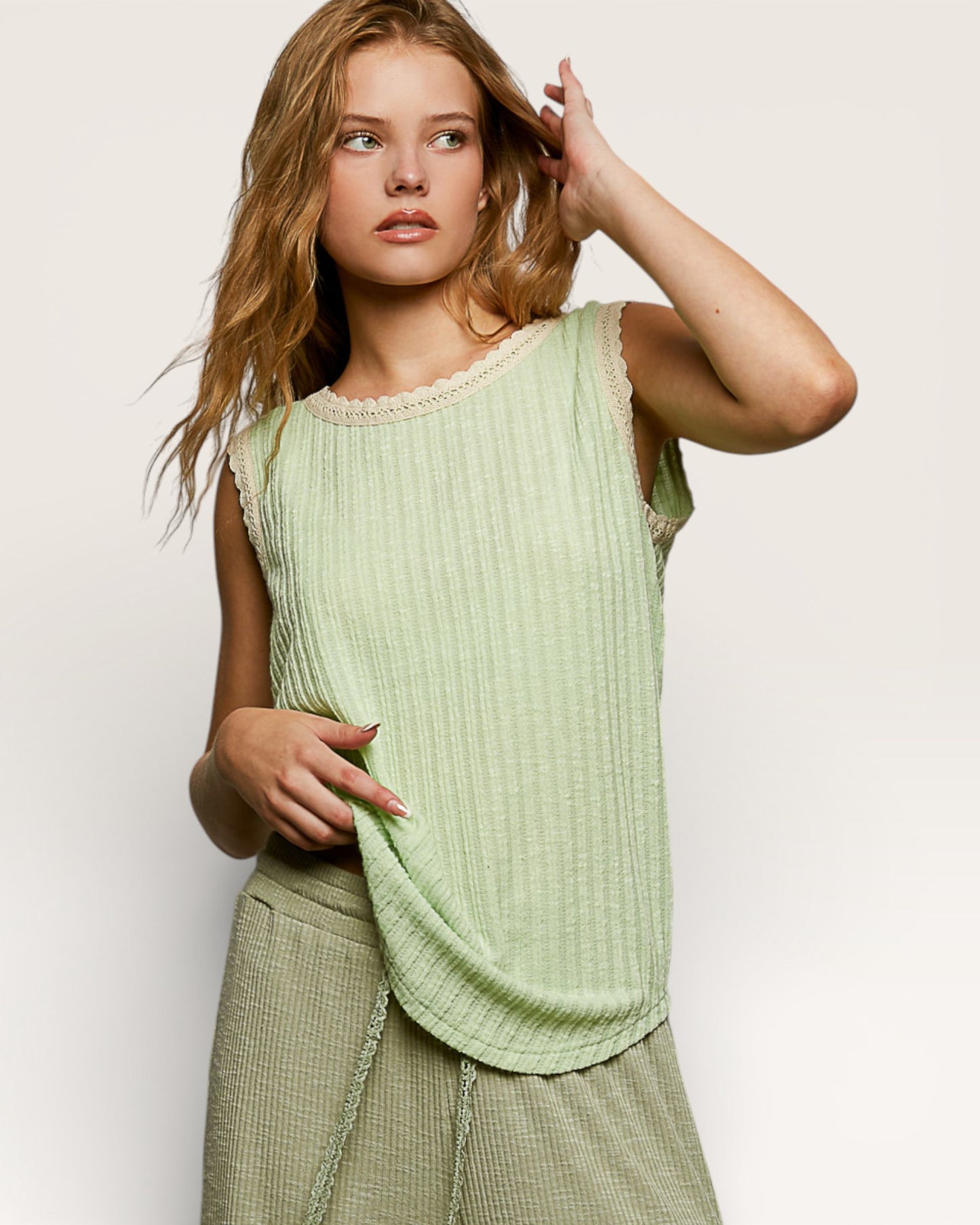 Woman wearing a light green sleeveless top against a plain background