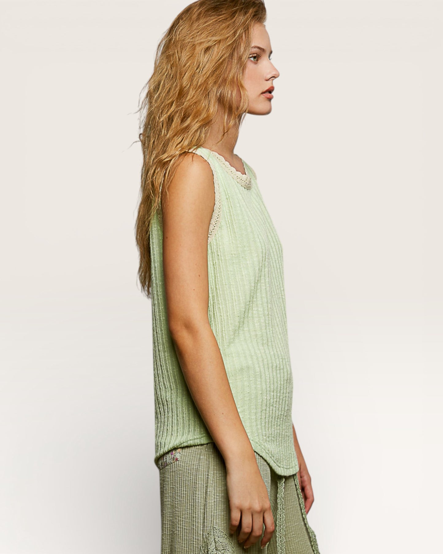 Woman wearing a light green sleeveless top against a plain background