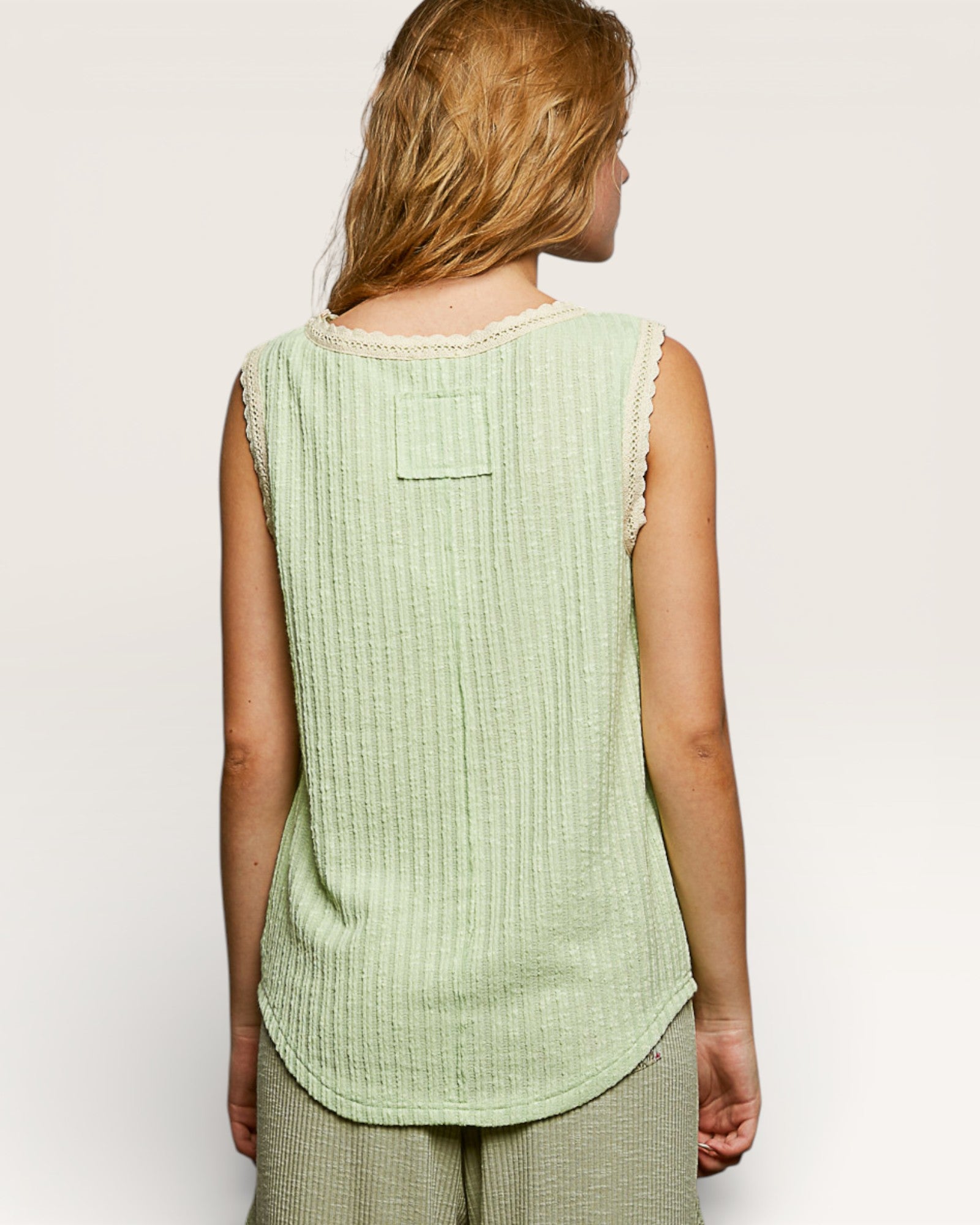 Woman wearing a light green sleeveless top against a plain background