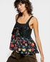 Woman wearing a black floral peplum top against a white background