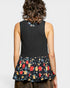 Person wearing a black sleeveless top with floral patterned hem on a plain background