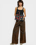Woman wearing a floral top and brown wide-leg pants on a white background