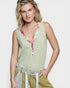 Woman wearing a light green sleeveless top with floral details on a white background