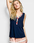 Woman wearing a navy sleeveless top with a colorful neckline on a light gray background