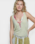 Woman wearing a light green sleeveless top with floral details on a white background