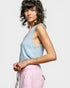 Woman wearing a light blue sleeveless top and pink pants against a white background