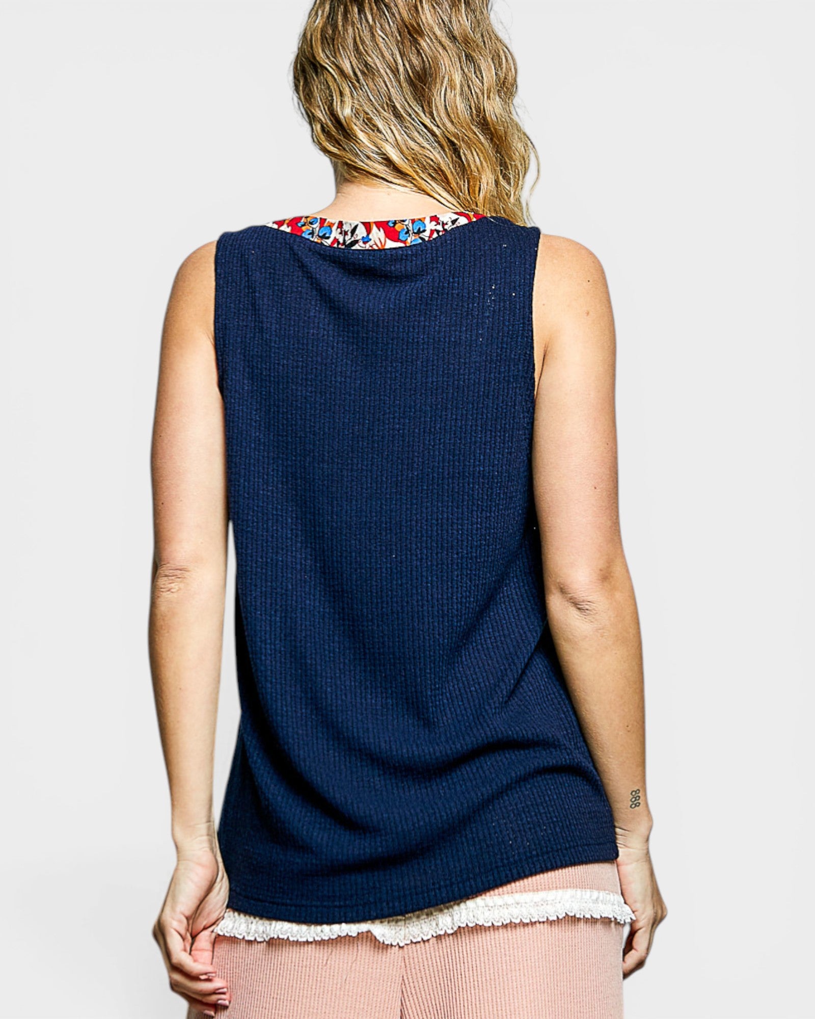 Woman wearing a navy sleeveless top with a colorful collar on a light gray background