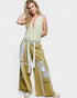 Woman wearing a sleeveless top and wide-leg pants with patchwork details on a white background