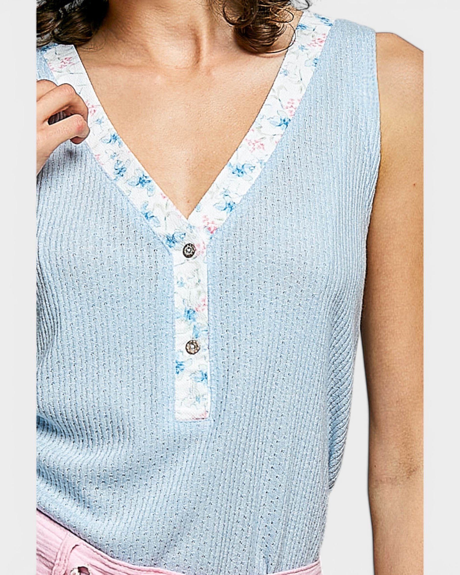 Light blue sleeveless top with floral trim on a plain background