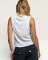 Person wearing a white sleeveless top and dark pants on a plain background