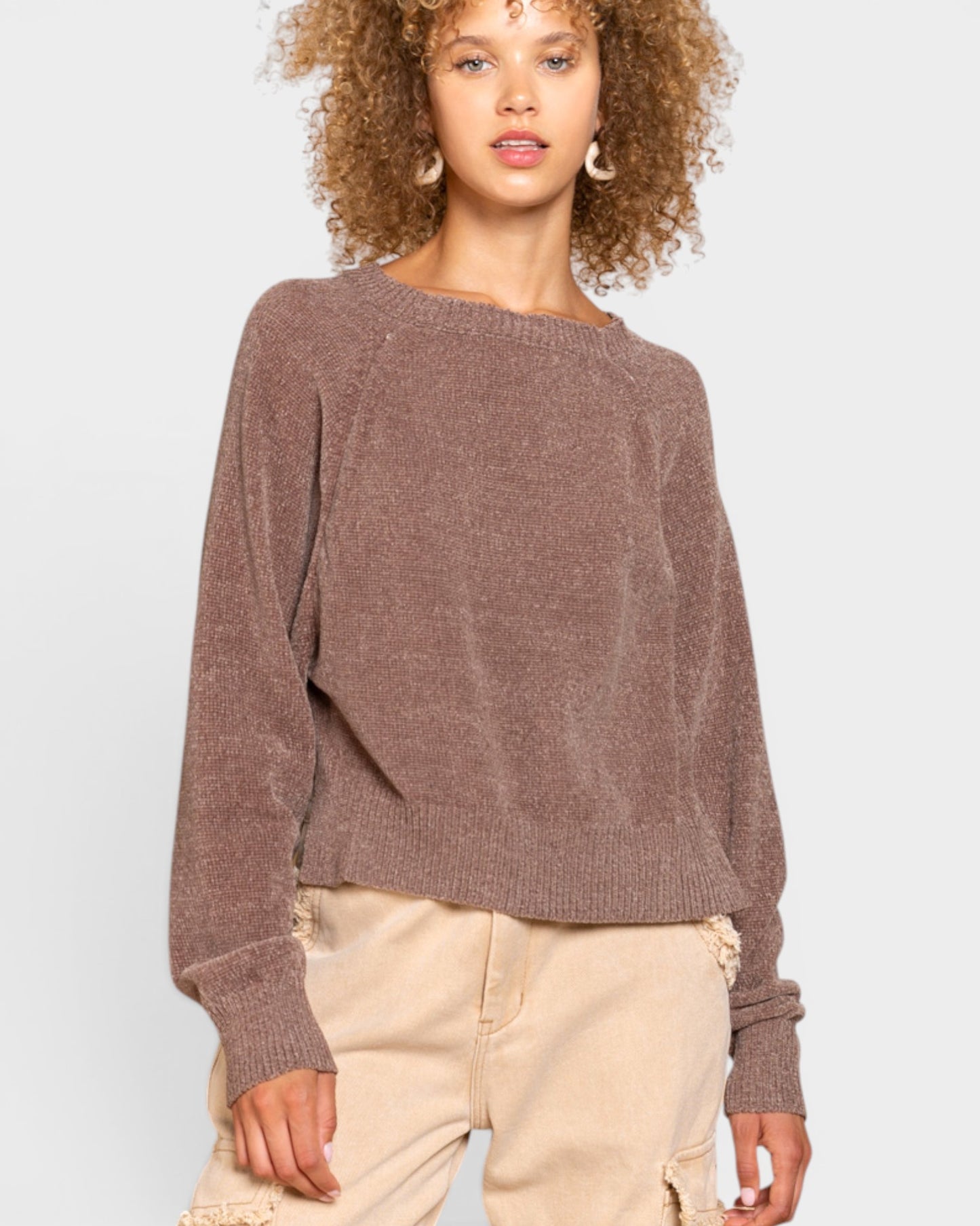 Woman wearing a brown sweater and beige pants on a white background