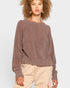 Woman wearing a brown sweater and beige pants on a white background